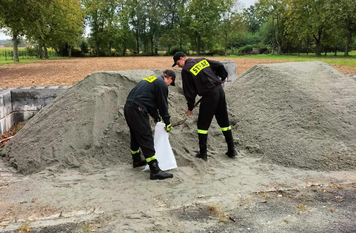 strażacy ładujący piasek do worków