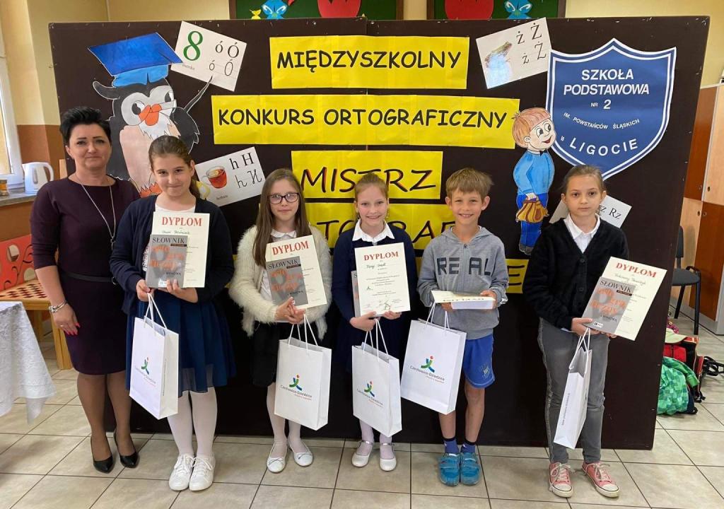 dyrektorka szkoły z laureactami konkursu ortograficznego, trzymają dyplomy i nagrody