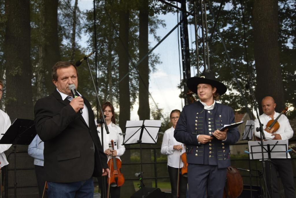 na scenie stoją dwaj mężczyźni: sołtys zabrzeg oraz konferansjer, w tle muzycy z kapeli