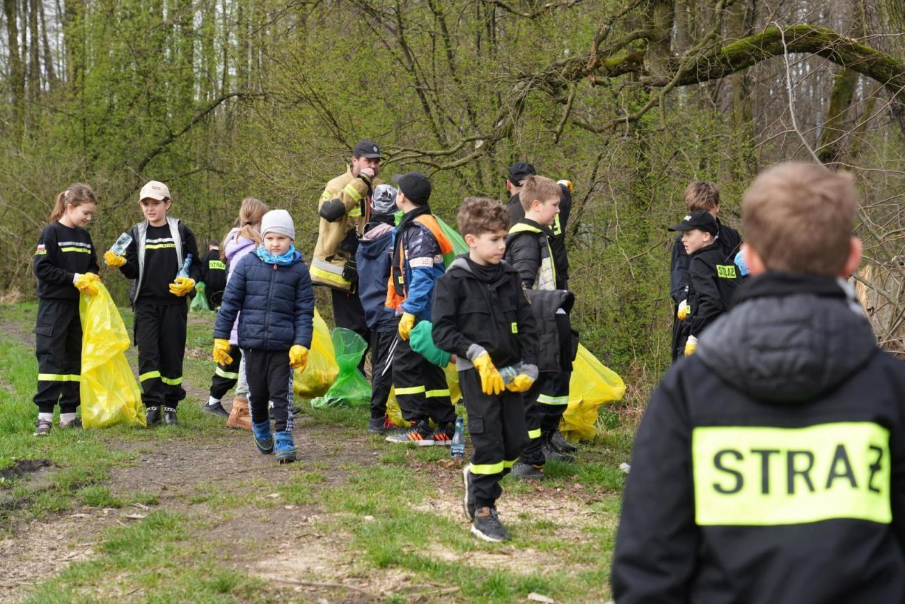 dzieci z młodzieżowej drużyny pożarniczej sprzątający zagajnik