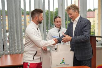 burmistrz wręczający sportowcom zestaw upominkowy