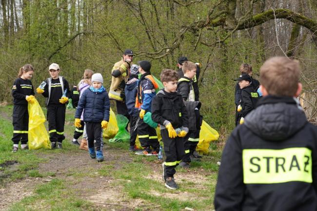 dzieci z młodzieżowej drużyny pożarniczej sprzątający zagajnik