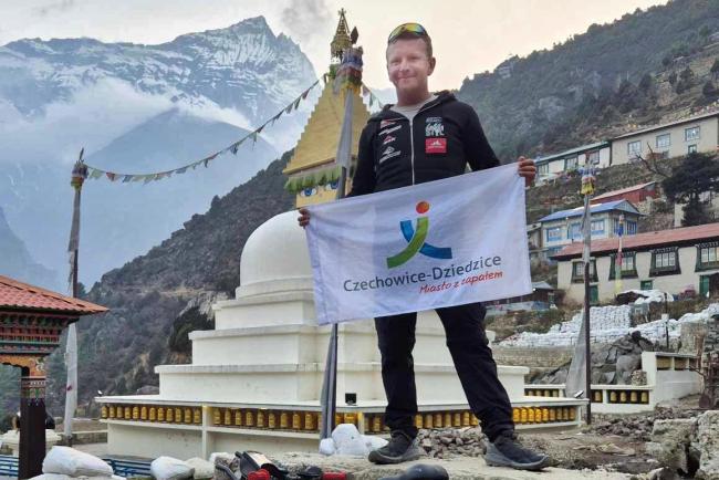 mężczyzna trzymający flagę z logo Gminy Czechowice-Dziedzice na tle gór